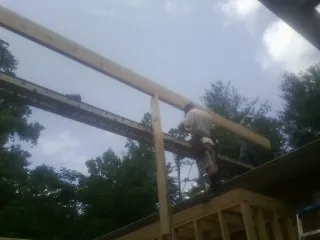 Carpenter setting a ridge beam over a new addition frame — Ice Dam Removal by Roofing Brothers in Siler City