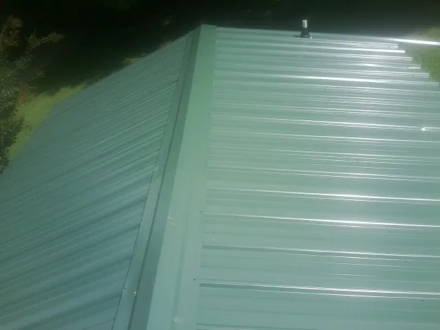 New green metal panels meeting at the ridge of a roof — Flat Roof Repair work by our crew in Siler City