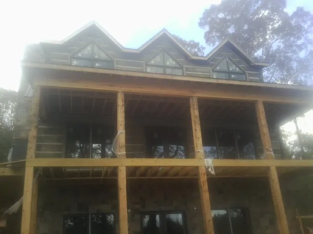 Dormers and porch framing on a large log home under construction — Roof Coating work by our crew in Siler City