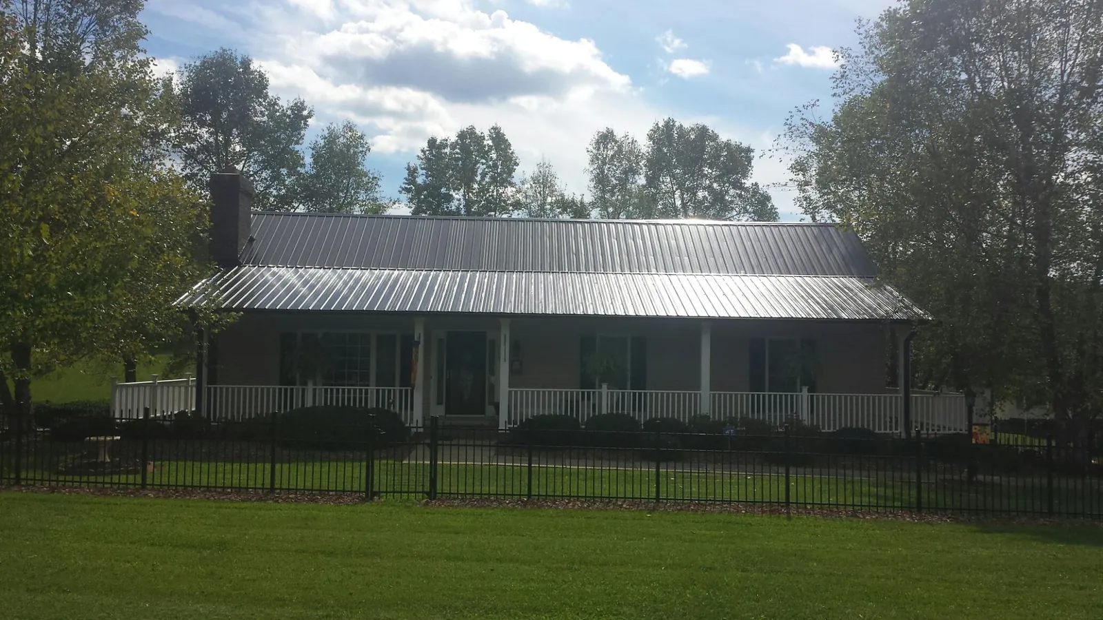 Gray metal roof on a brick ranch with a full width front porch — Gutter Guard Installation work by our crew in Siler City