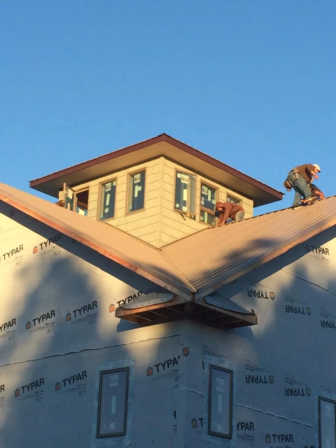 Roofers working around a rooftop cupola on a new metal roof at sunset — Roof Waterproofing in Siler City by Roofing Brothers